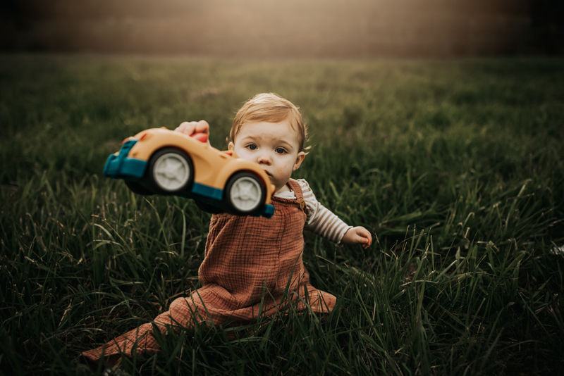 Family Photography, little boy sitting in the grass playing with a toy car
